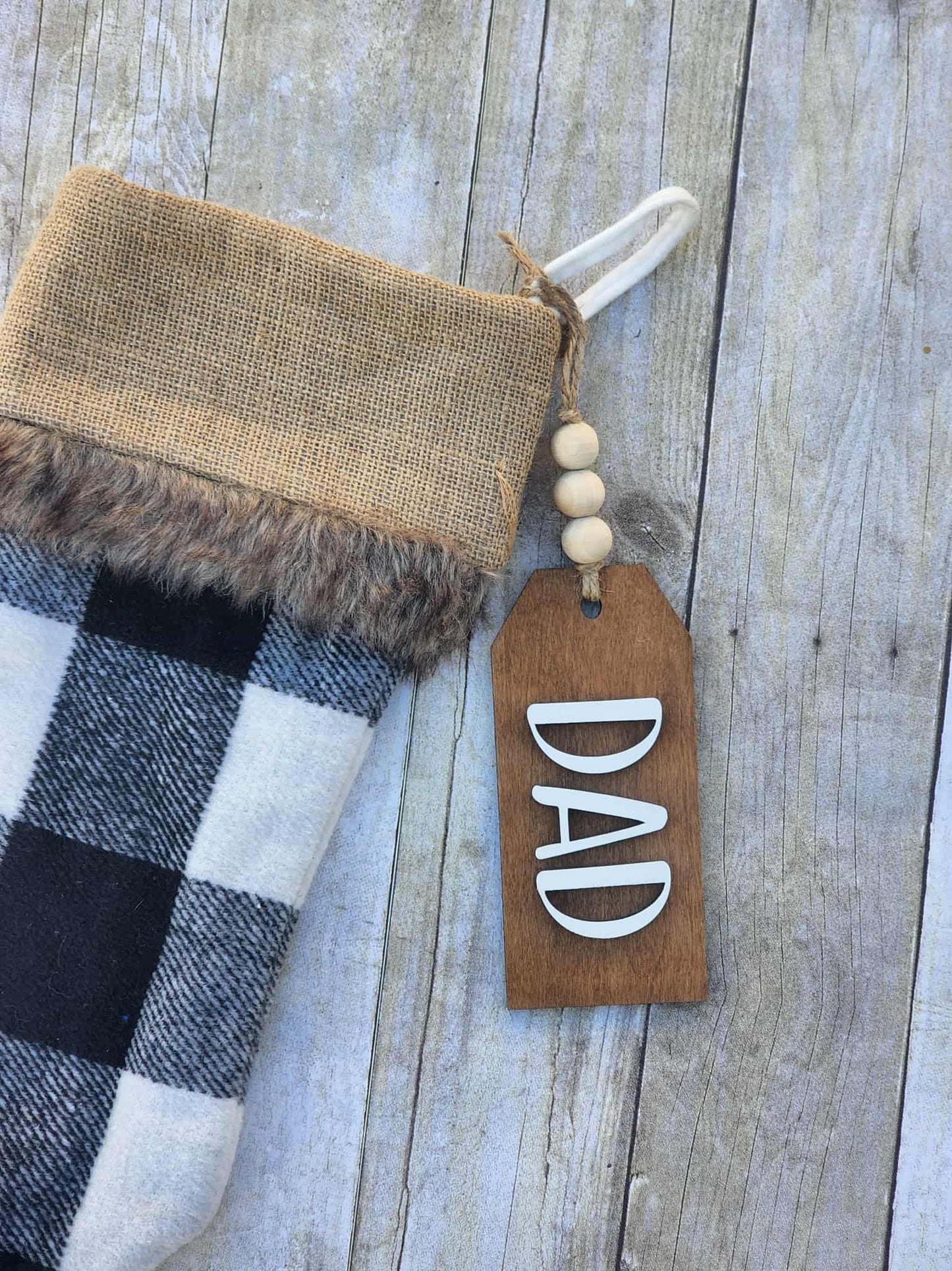 Decorative stocking with burlap and fur trim, featuring a 'DAD' tag on a wooden surface.