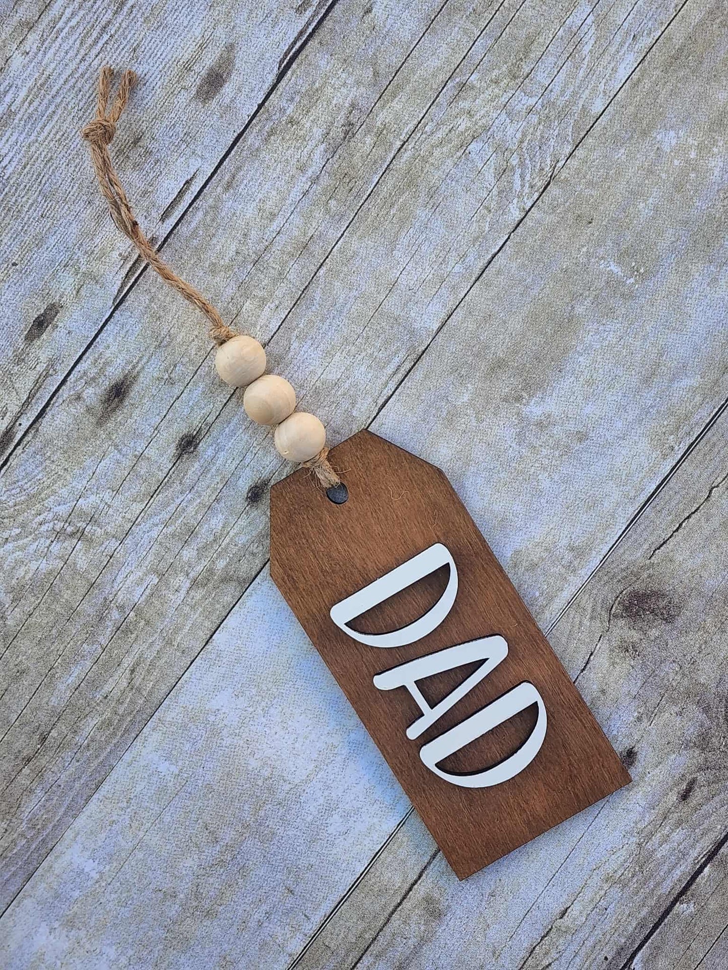 Wooden tag with 'DAD' on a rustic wooden surface