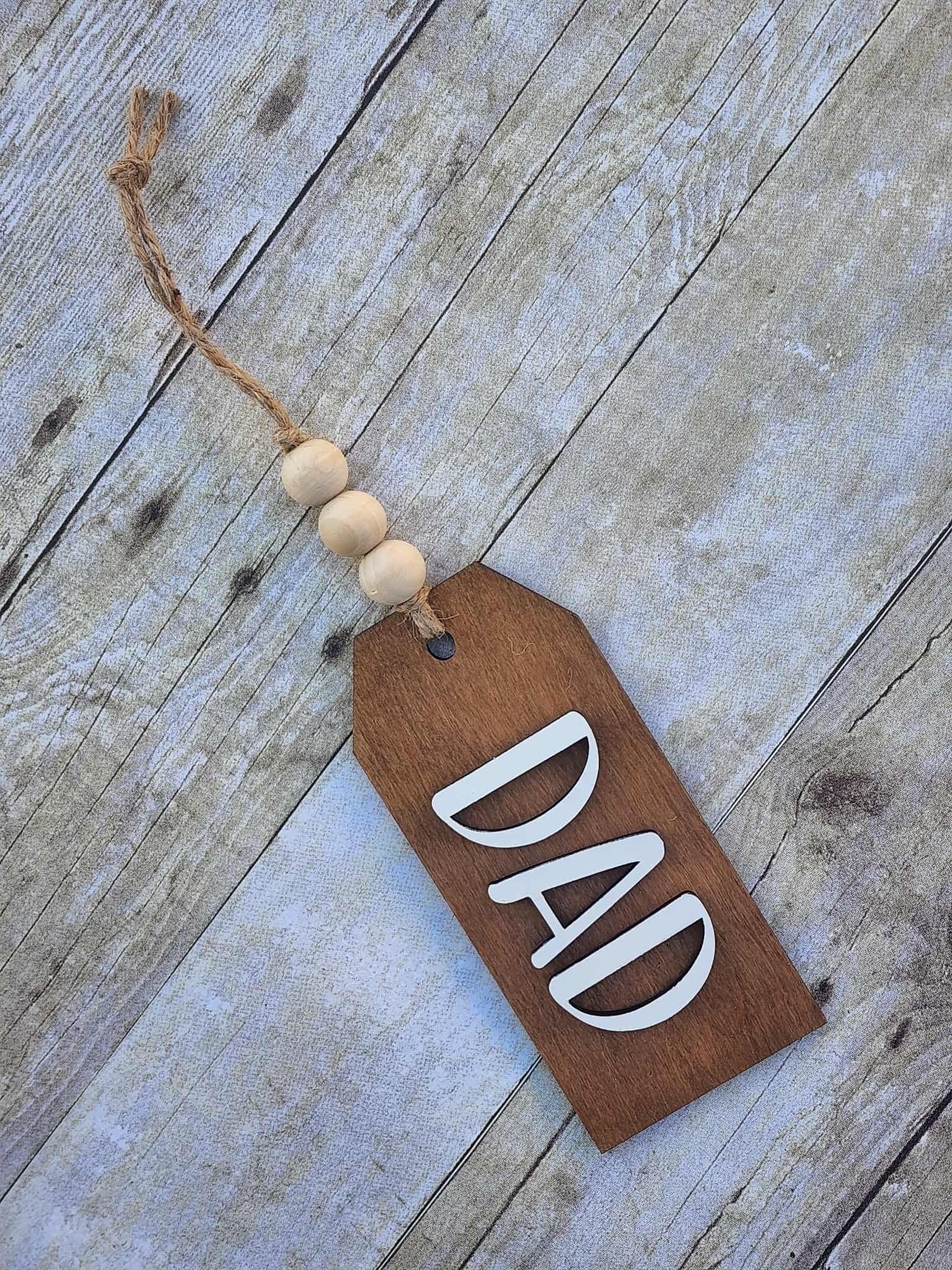 Wooden tag with 'DAD' on a rustic wooden surface